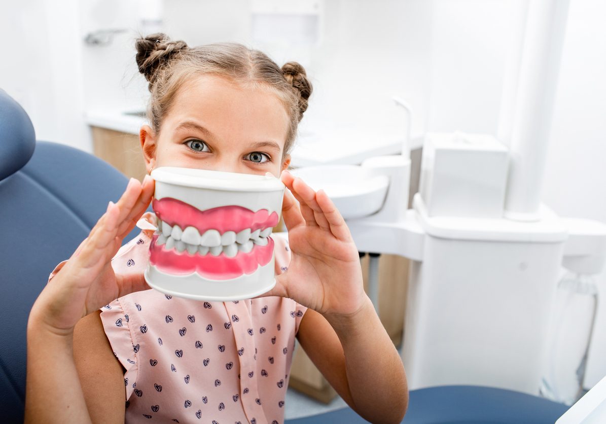 Teeth care. Emotional little girl sitting in the dentist's chair and smiling