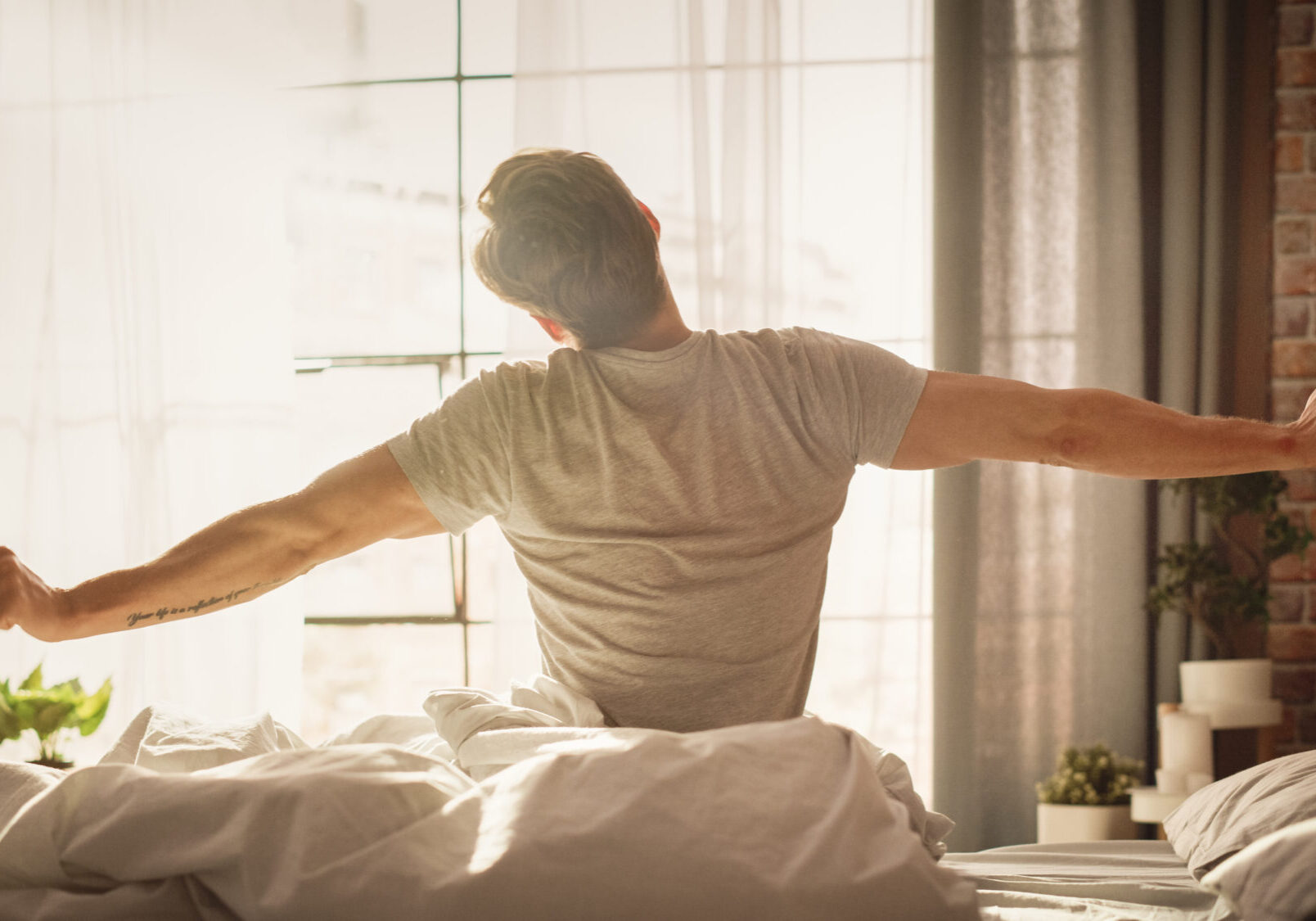 Handsome Young Man Waking up in the Morning, Stretches and Gets Out of Bed, Sun Shines From the Apartment Window in Bedroom, He is Ready for Business Opportunities, Achievements, Adventures